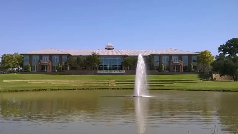Keller City Hall across a pond with a fountain on a clear day