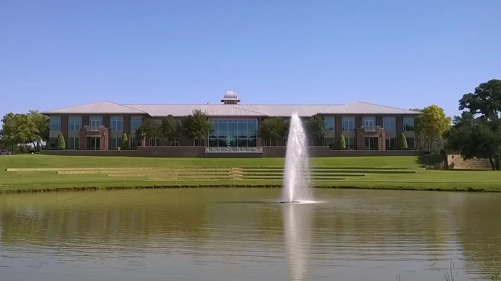 Keller City Hall across a pond with a fountain on a clear day
