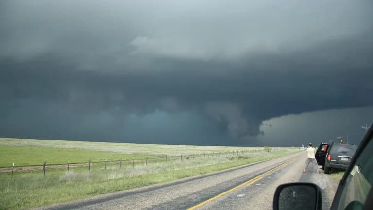 A dark storm cloud over green grassland beside a rural highway in the Texas Panhandle