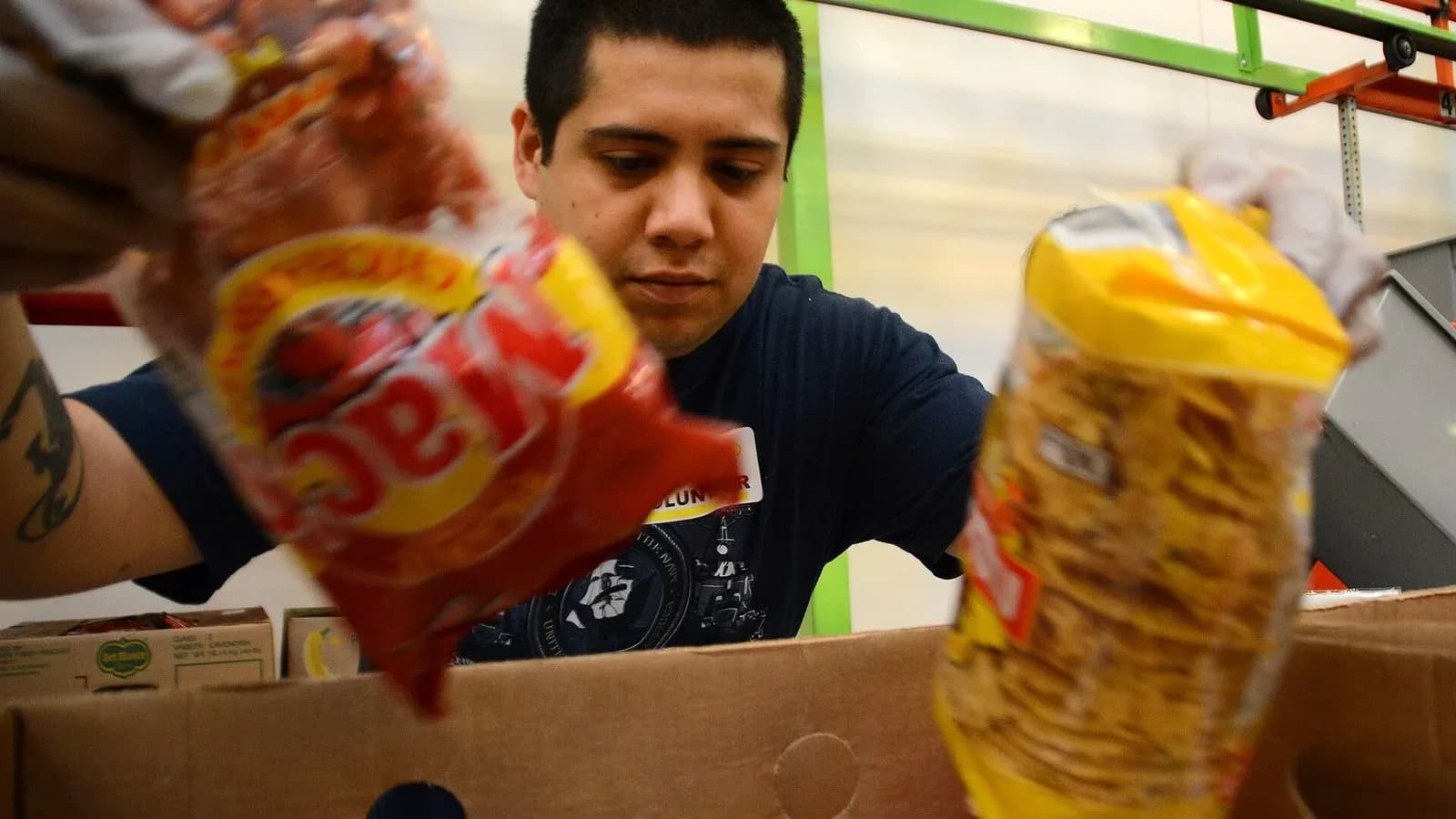 A volunteer sorts bags of dried food into a box at the Houston Food Bank