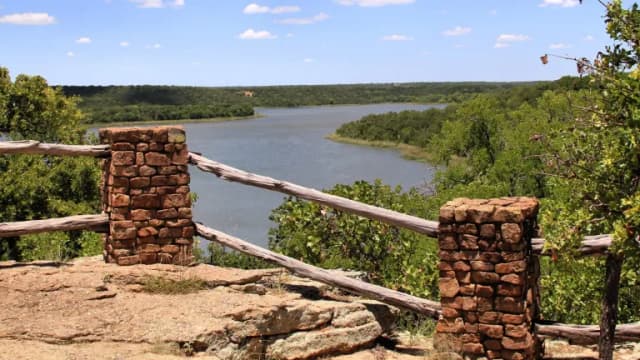 A rustic stone-and-rail overlook above Lake Mineral Wells surrounded by green hills