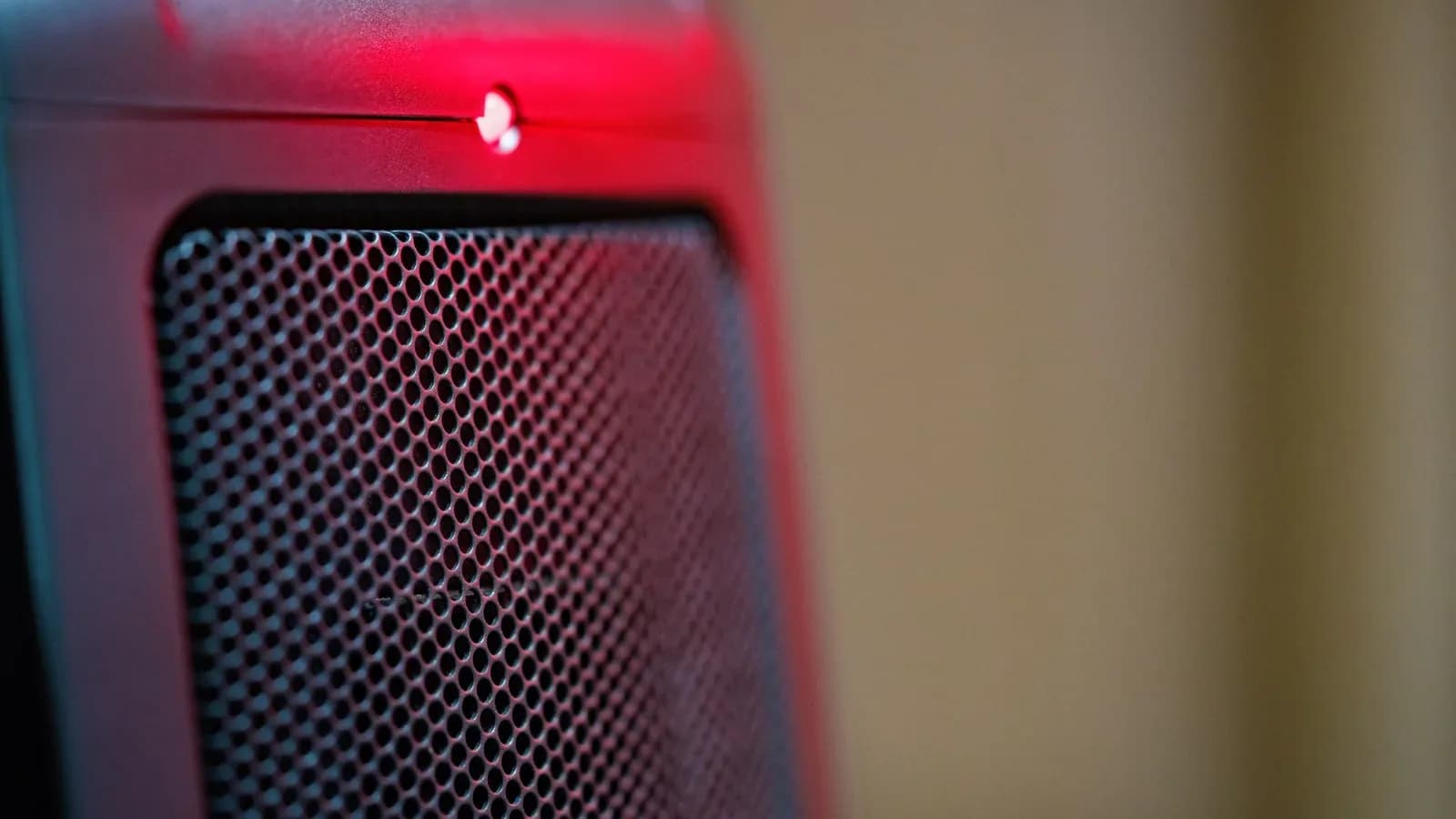 Close-up of the front grille of an electric ceramic space heater with a glowing red indicator light