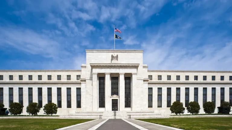 The white marble Eccles Building, headquarters of the Federal Reserve, under a blue sky with an American flag on top