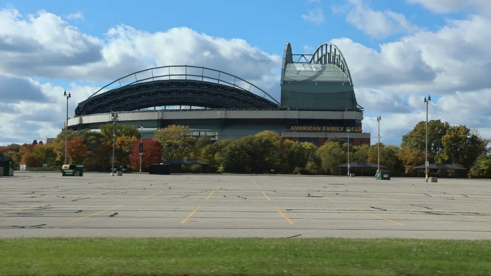 American Family Field, the Milwaukee Brewers' ballpark, seen across an empty parking lot with fall trees