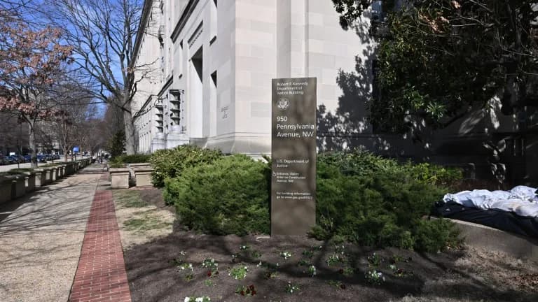 The corner of the Robert F. Kennedy Department of Justice Building in Washington, with its address sign among shrubs