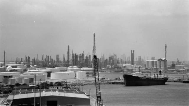 Black-and-white view of a tanker, docks and refineries along the Corpus Christi harbor