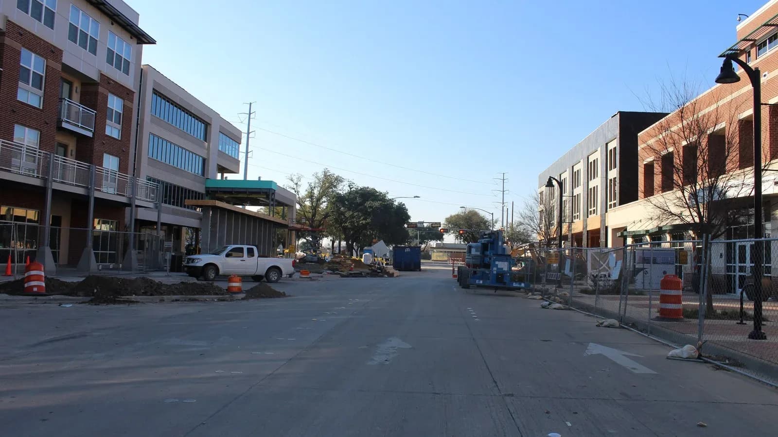 A downtown Garland street lined with brick and glass buildings, with construction fencing and equipment