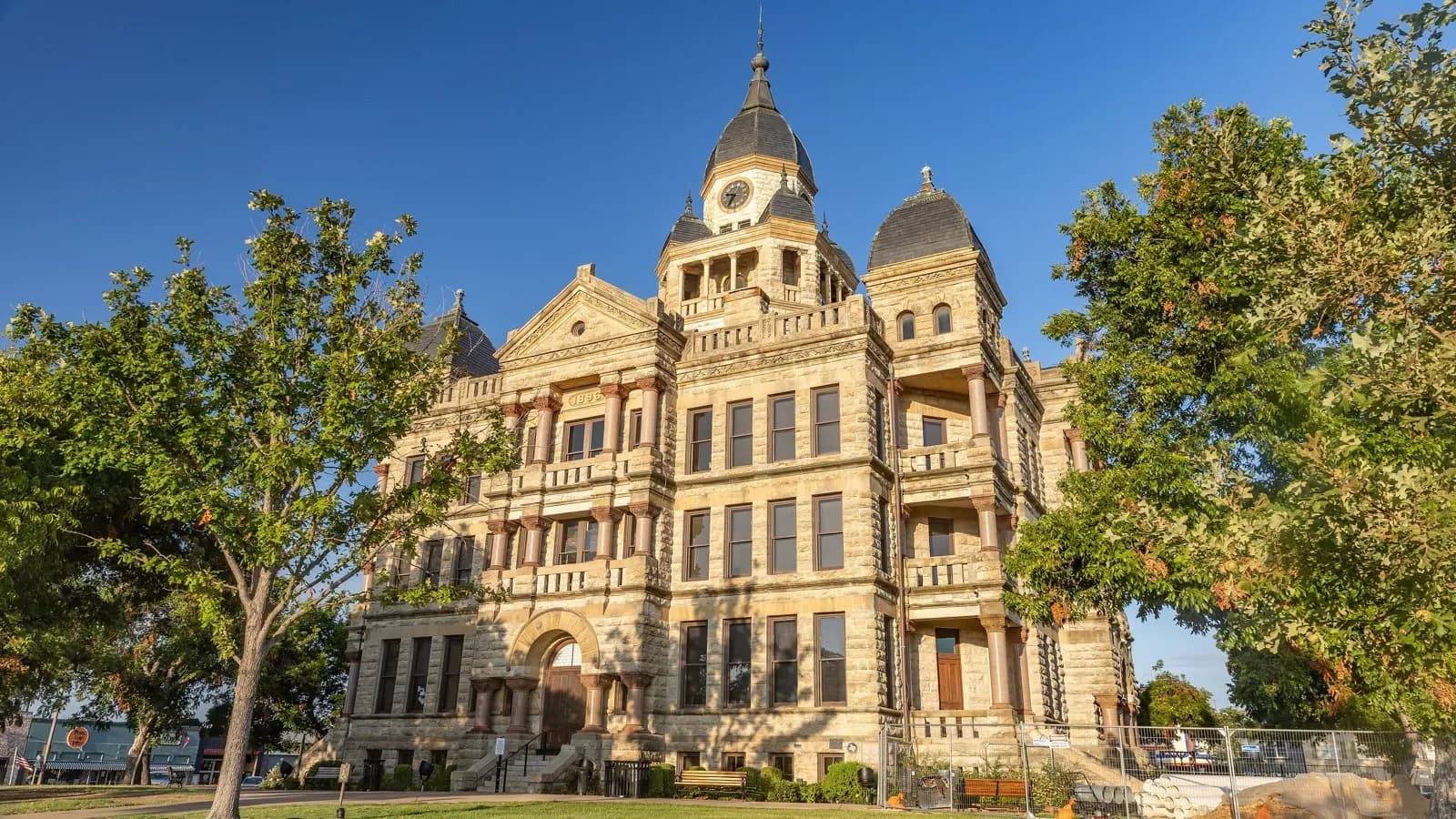 The tan stone 1896 Denton County Courthouse with a central clock tower and domed turrets