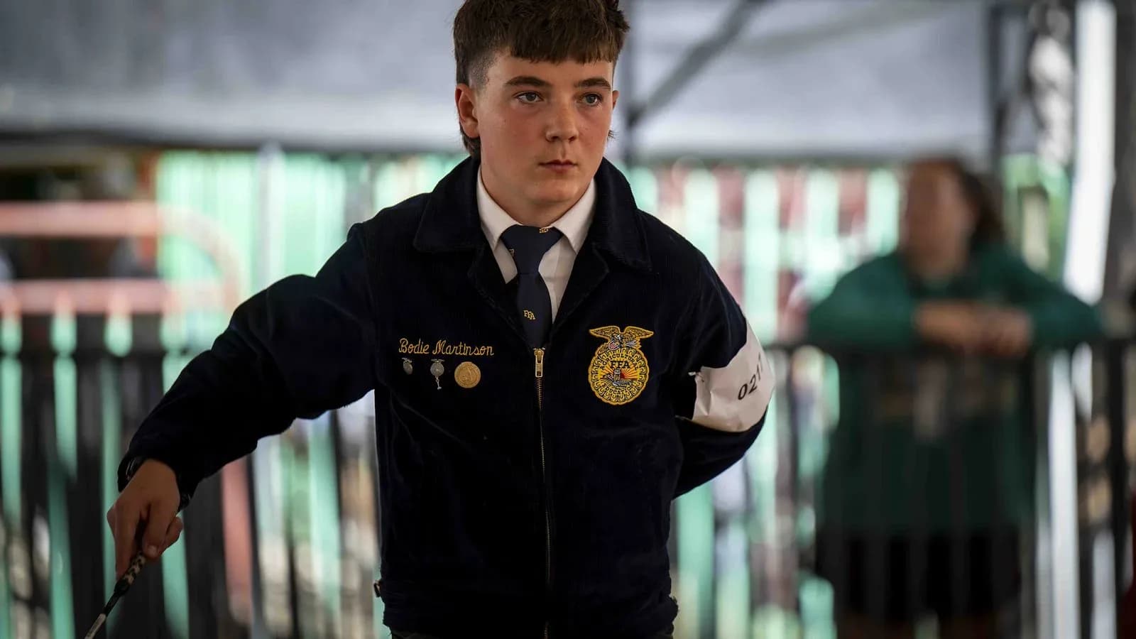 FFA member in a blue corduroy jacket at a youth livestock show (illustrative)