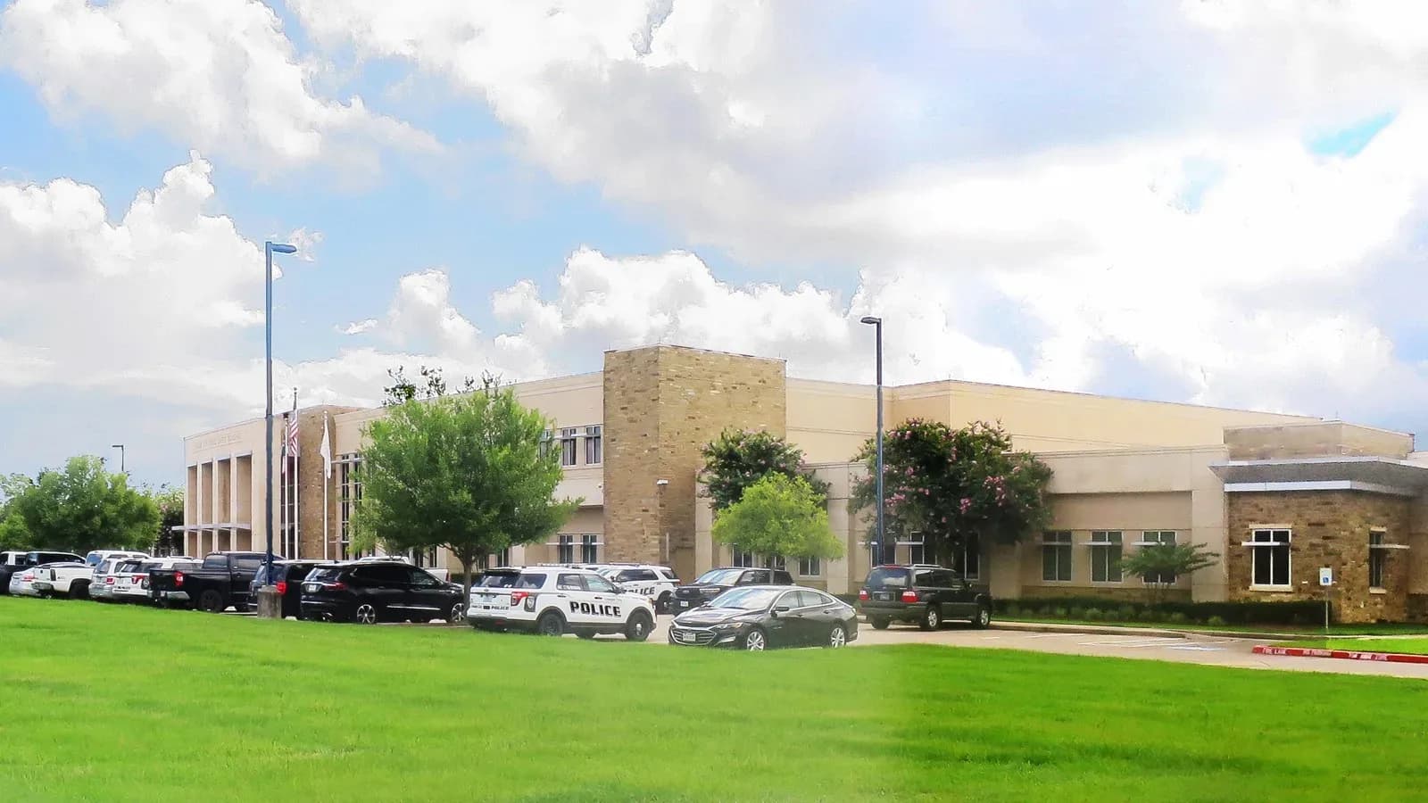 The League City Police Department building with patrol cars and other vehicles parked out front under a cloudy sky