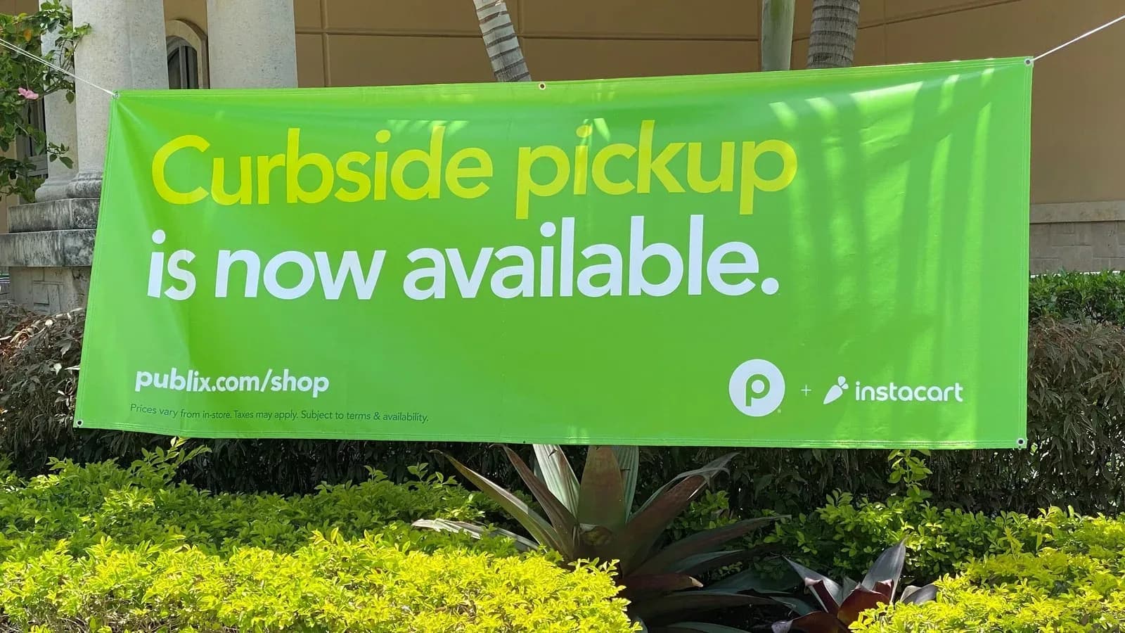 A green banner reading Curbside pickup is now available with Publix and Instacart logos outside a store in West Miami, Florida