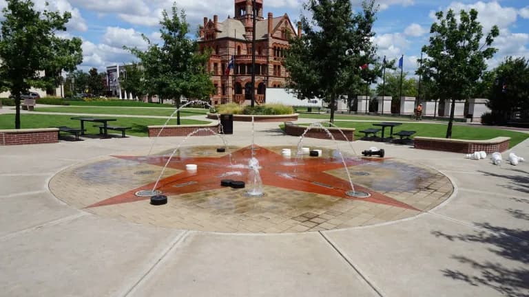 A splash pad with a red star on the courthouse square in Sulphur Springs, with the Hopkins County Courthouse behind it