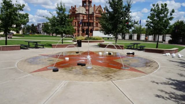 A splash pad with a red star on the courthouse square in Sulphur Springs, with the Hopkins County Courthouse behind it