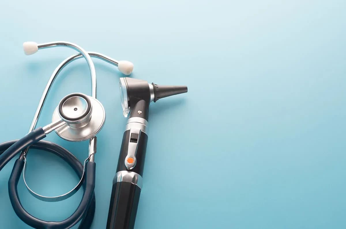 Otoscope with stethoscope on blue background.