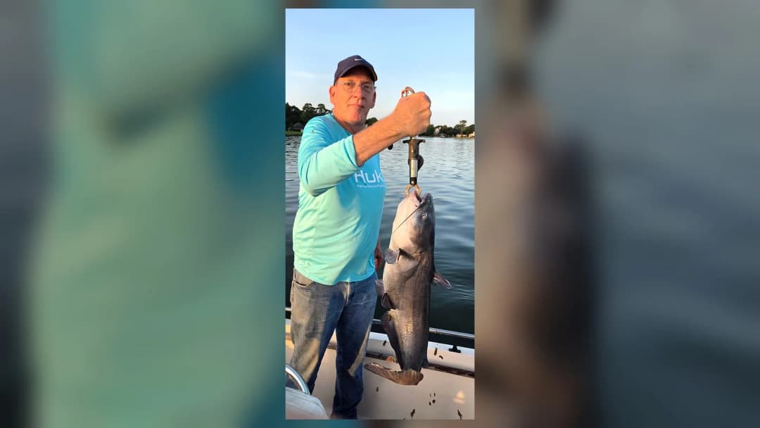 Steven holds a large Lake Conroe catfish from a boat during warm evening light