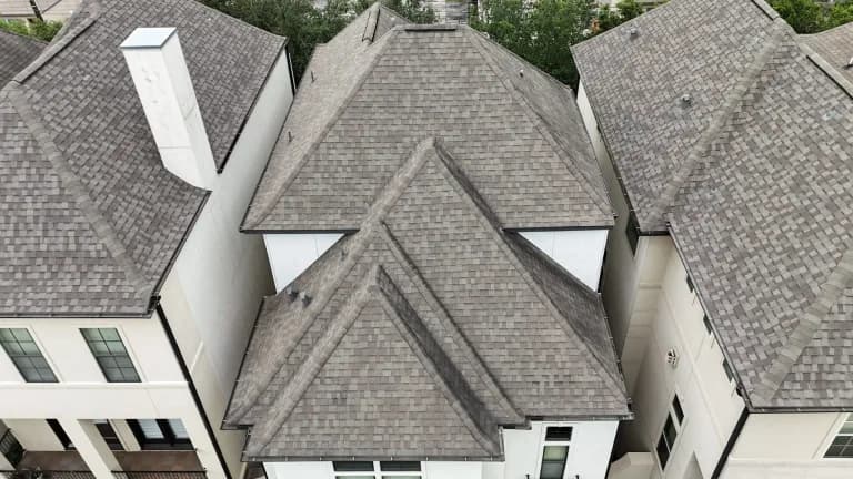 A light gray dimensional roof on a townhome, between neighboring shingle roofs.