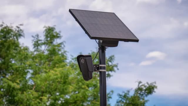 A Flock Safety license plate reader camera mounted on a pole with a solar panel
