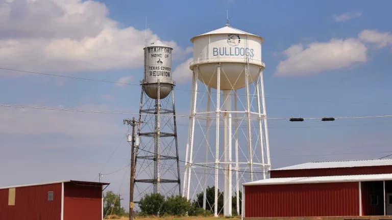 Two elevated water towers against a blue sky in a small Texas town