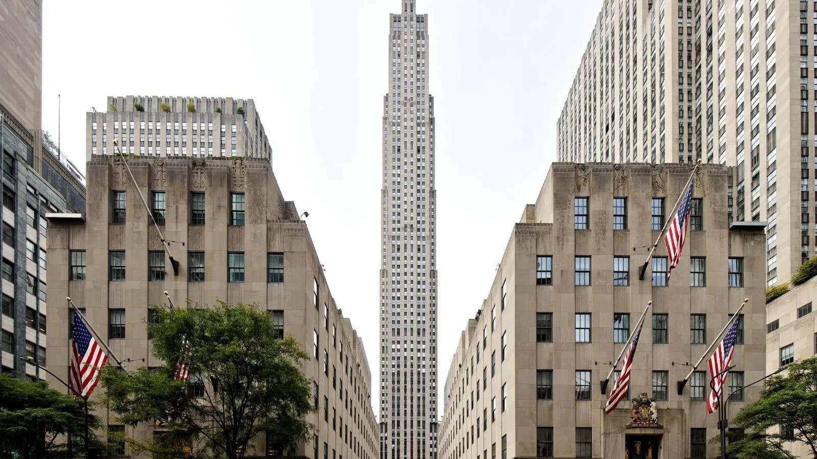 30 Rockefeller Plaza rising between two stone buildings flying American flags