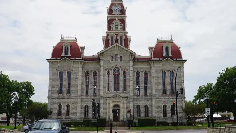 The ornate limestone Parker County Courthouse in Weatherford with red domed towers and a clock tower