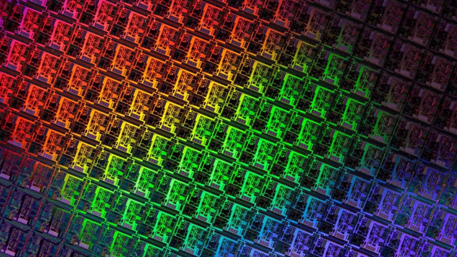 Close-up of a silicon wafer covered in rows of chips reflecting red, green and purple light