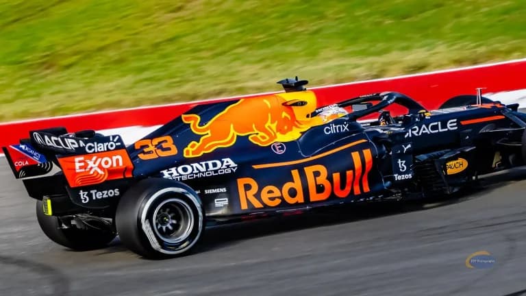 A dark blue Red Bull Formula 1 car with red and yellow livery racing past a curb at Circuit of the Americas