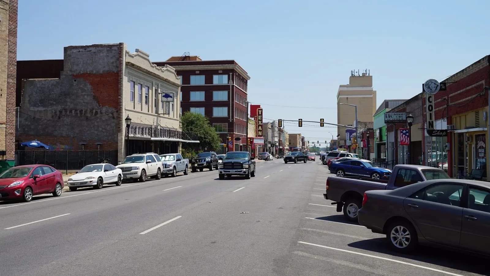 Lee Street in downtown Greenville with brick storefronts and parked cars under a clear sky