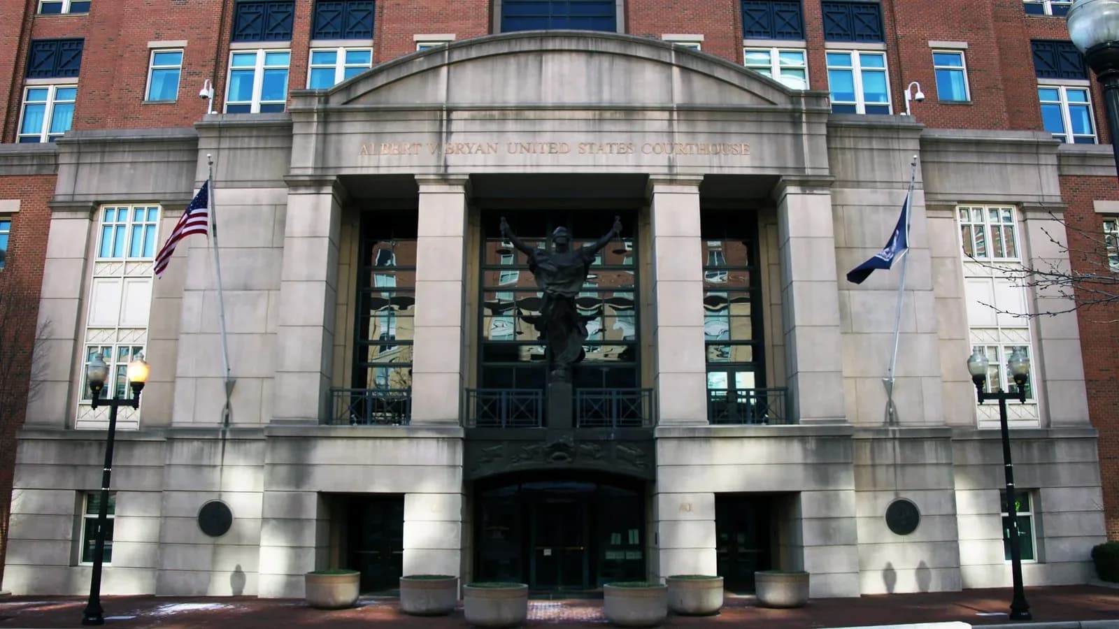 The Albert V. Bryan federal courthouse in Alexandria, Virginia, a stone and red brick building with a columned entrance and a bronze statue above the doors