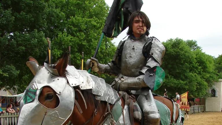 An armored knight on an armored horse holding a banner at a Texas Renaissance faire