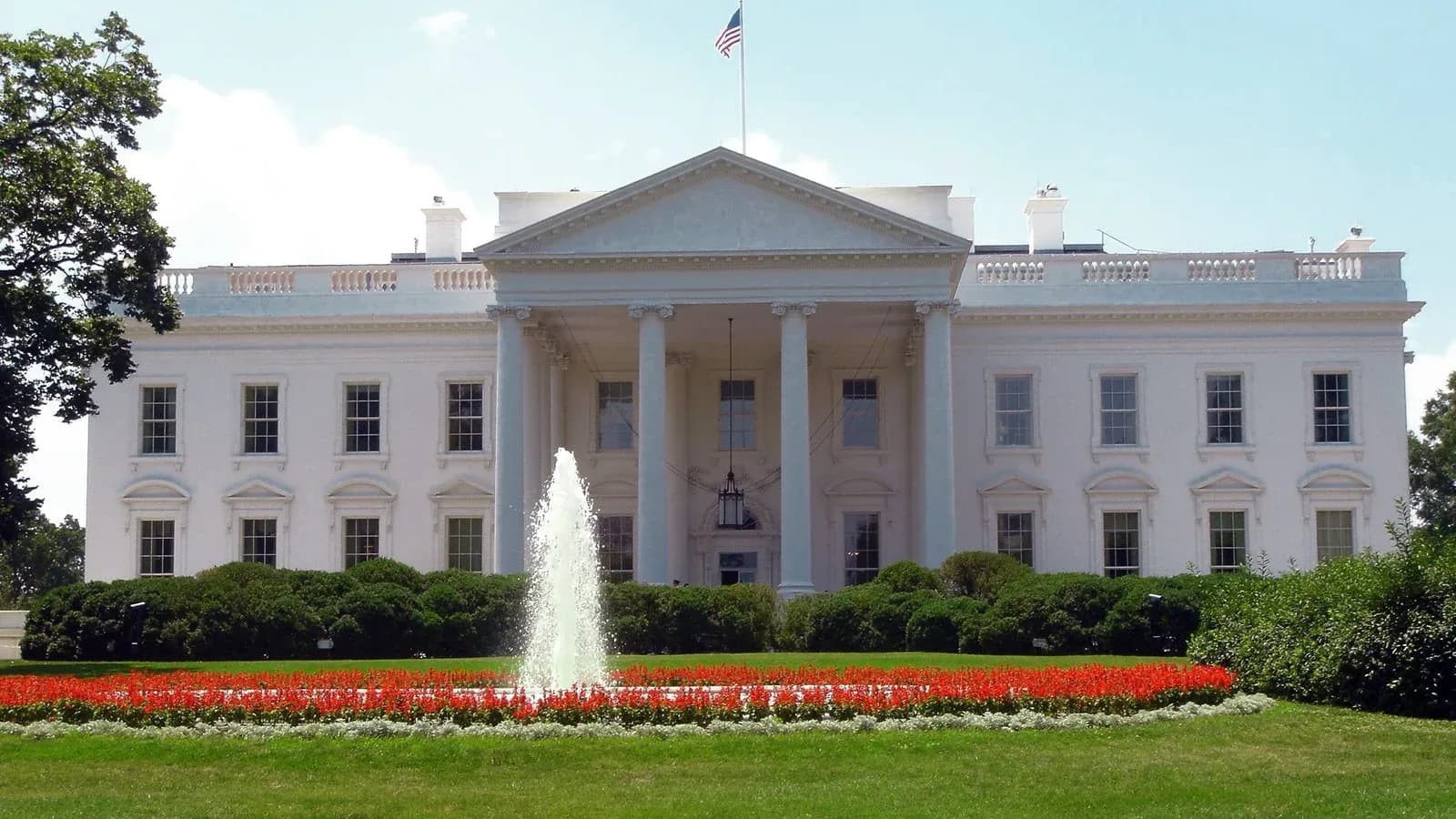 The north facade of the White House in Washington, with a fountain and red flower beds in front
