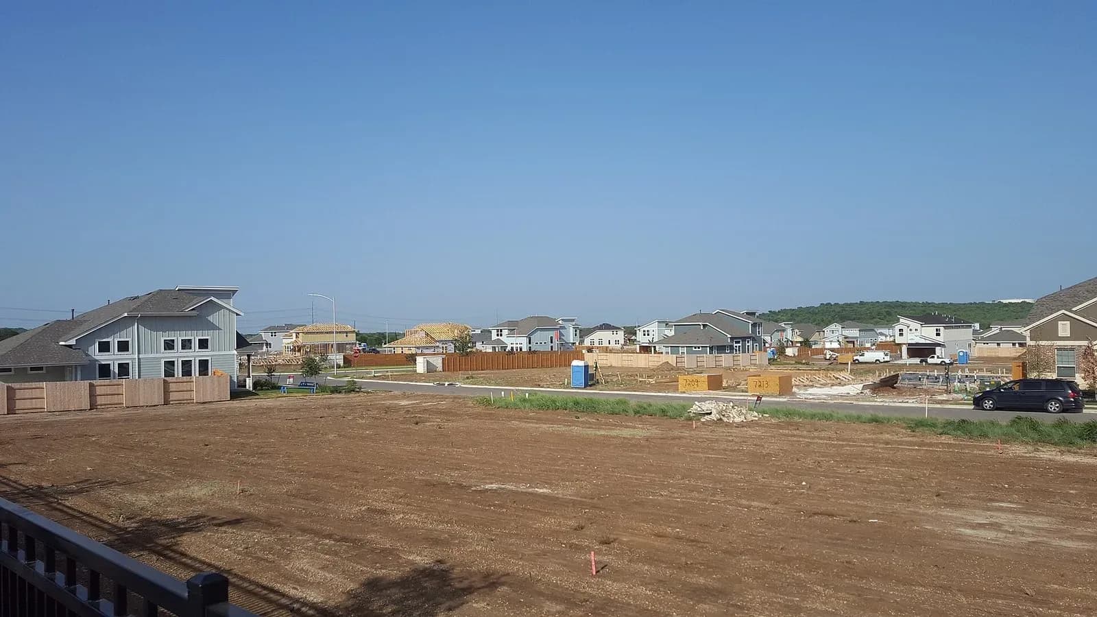 New houses and empty graded lots in a growing Austin subdivision under a clear sky