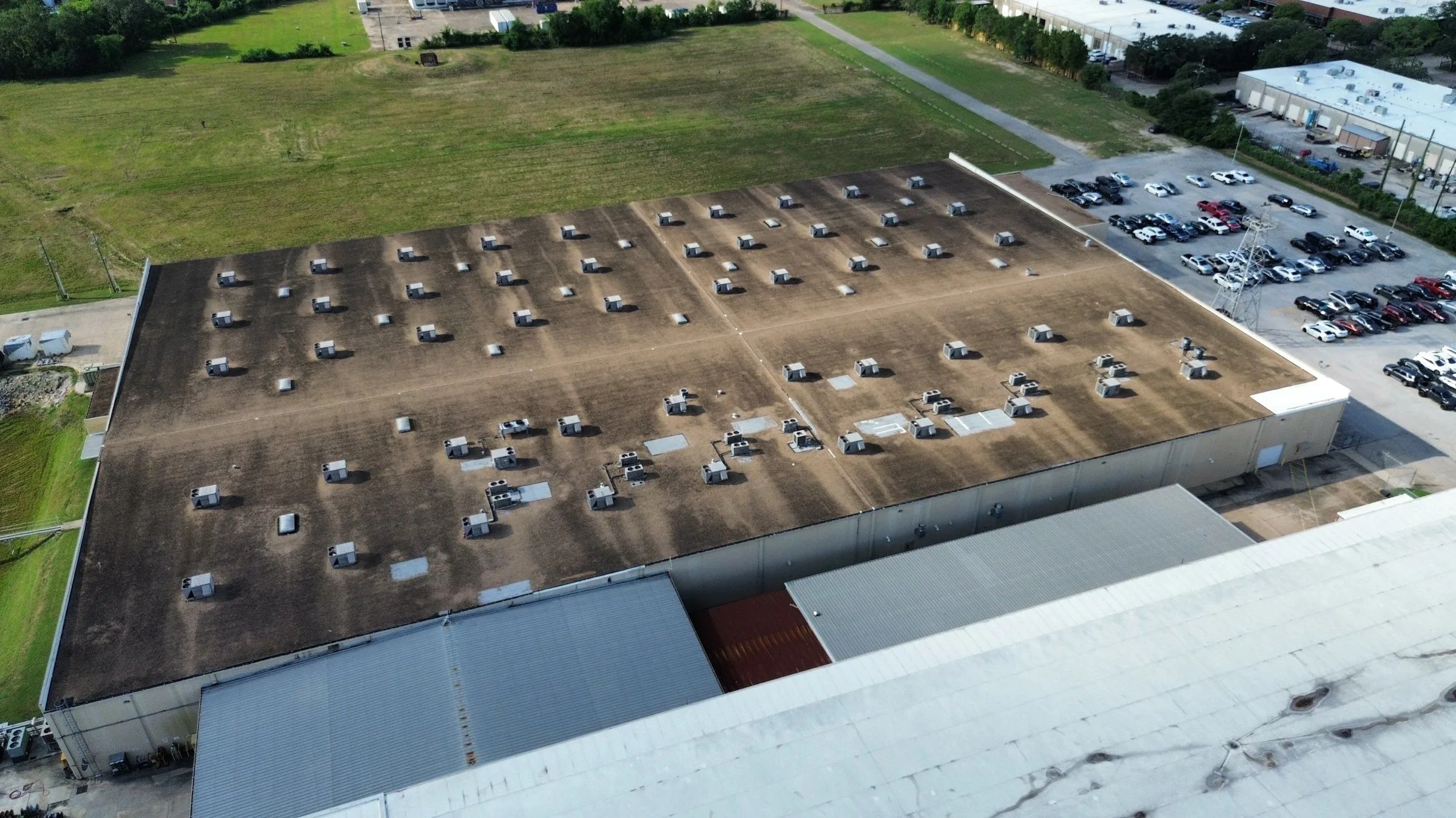 The same large commercial building with a dark, weathered flat roof before replacement.