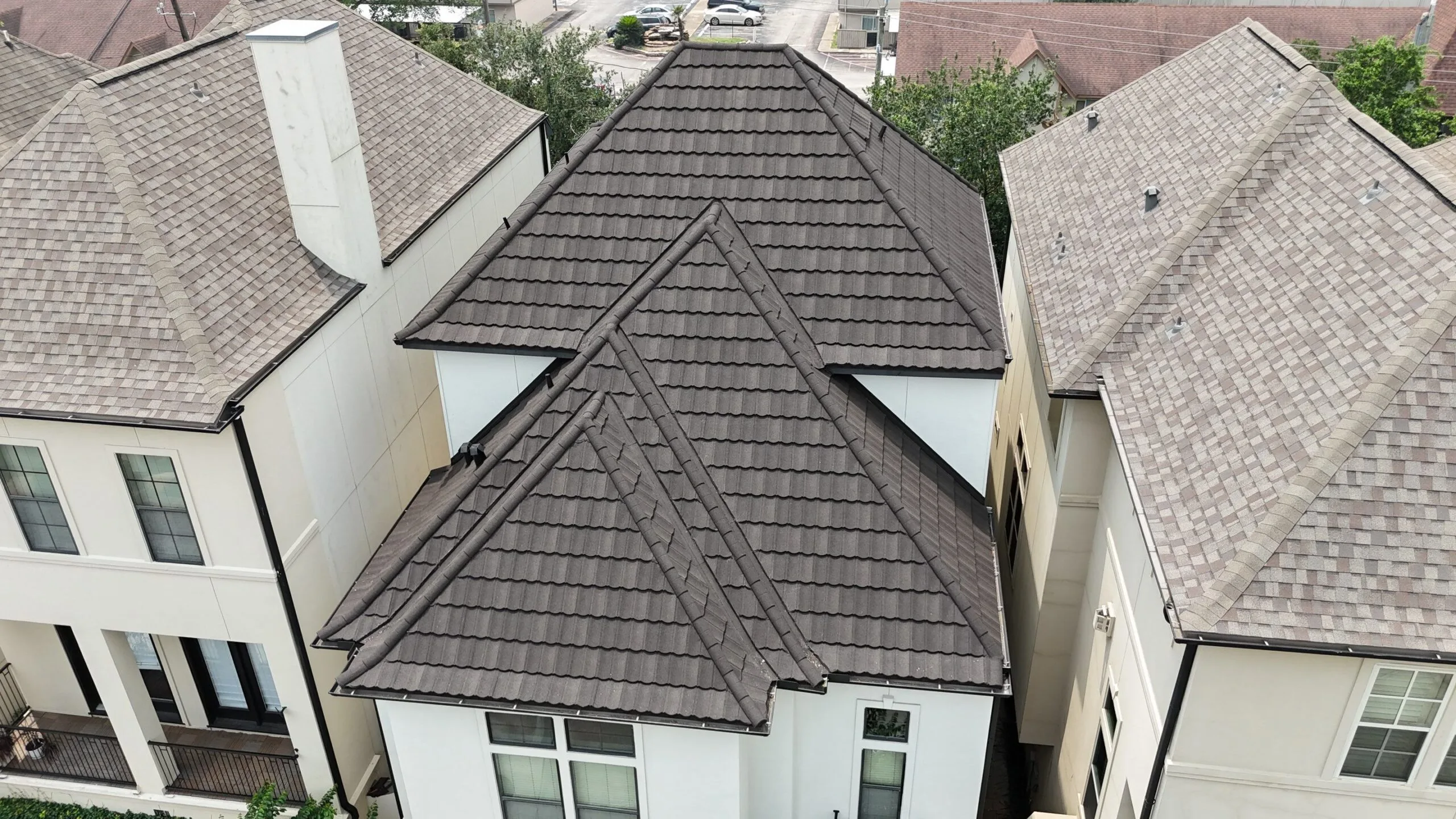 A dark tile-profile roof on a townhome building, before replacement.