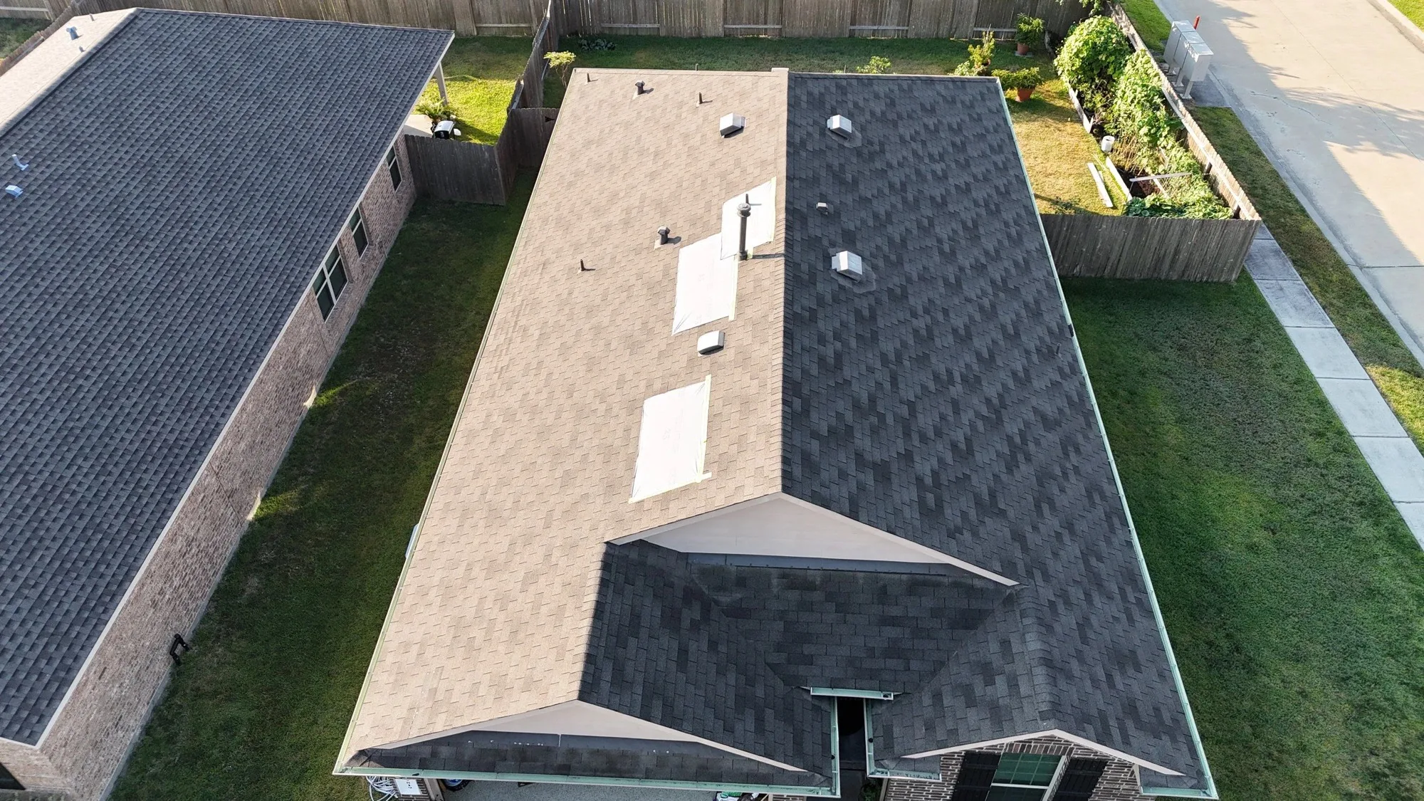 Aerial view of a shingle roof with temporary coverings over open spots