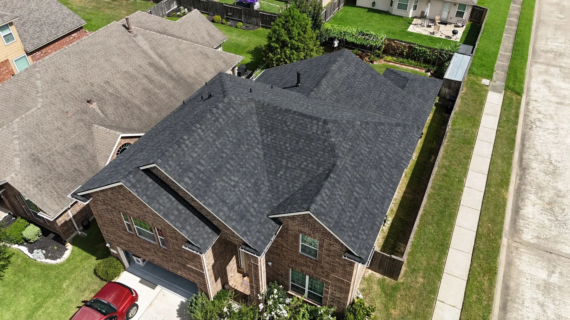 Completed dark gray shingle roof on a brick Houston-area house