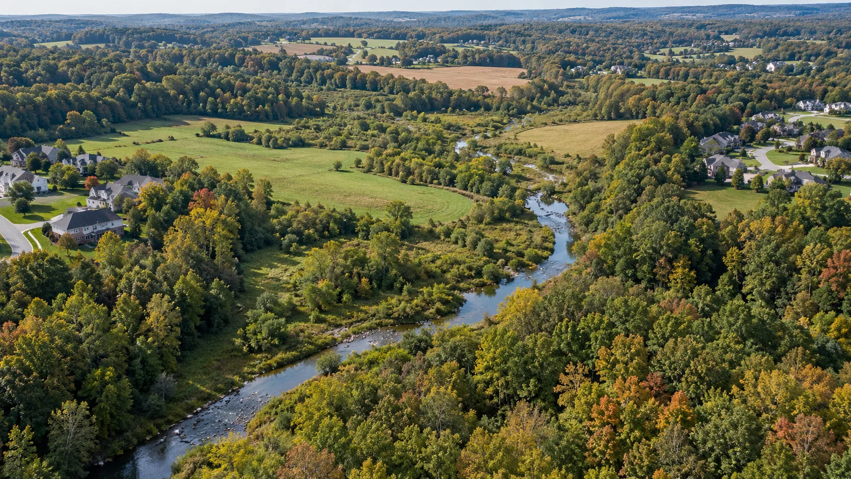 Wooded northern Delaware valley with a stream, open space and homes at the edges. AI-generated editorial illustration; not a photograph of the named project or intersection.
