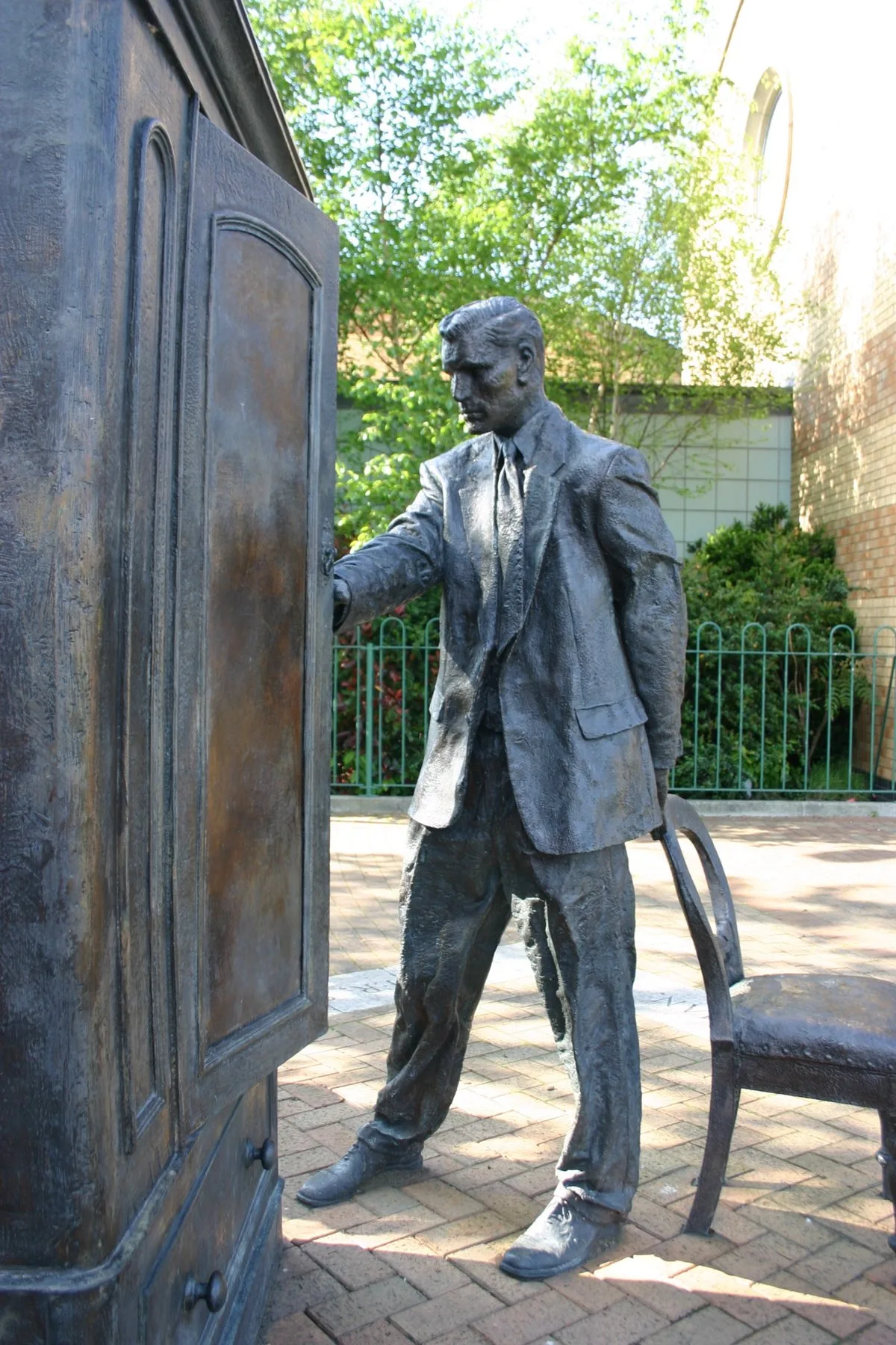 Bronze statue of C.S. Lewis opening a wardrobe door, titled The Searcher, in Belfast
