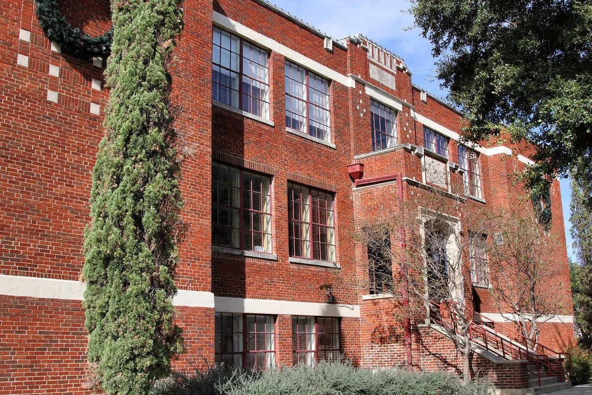 Killeen City Hall, a red brick former school building with tall windows, partly framed by trees