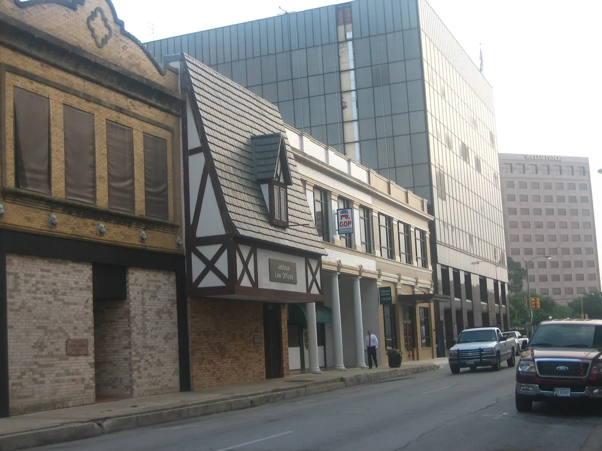 A street of older storefronts, including one with a half-timbered front, beside a glass office tower in downtown Victoria