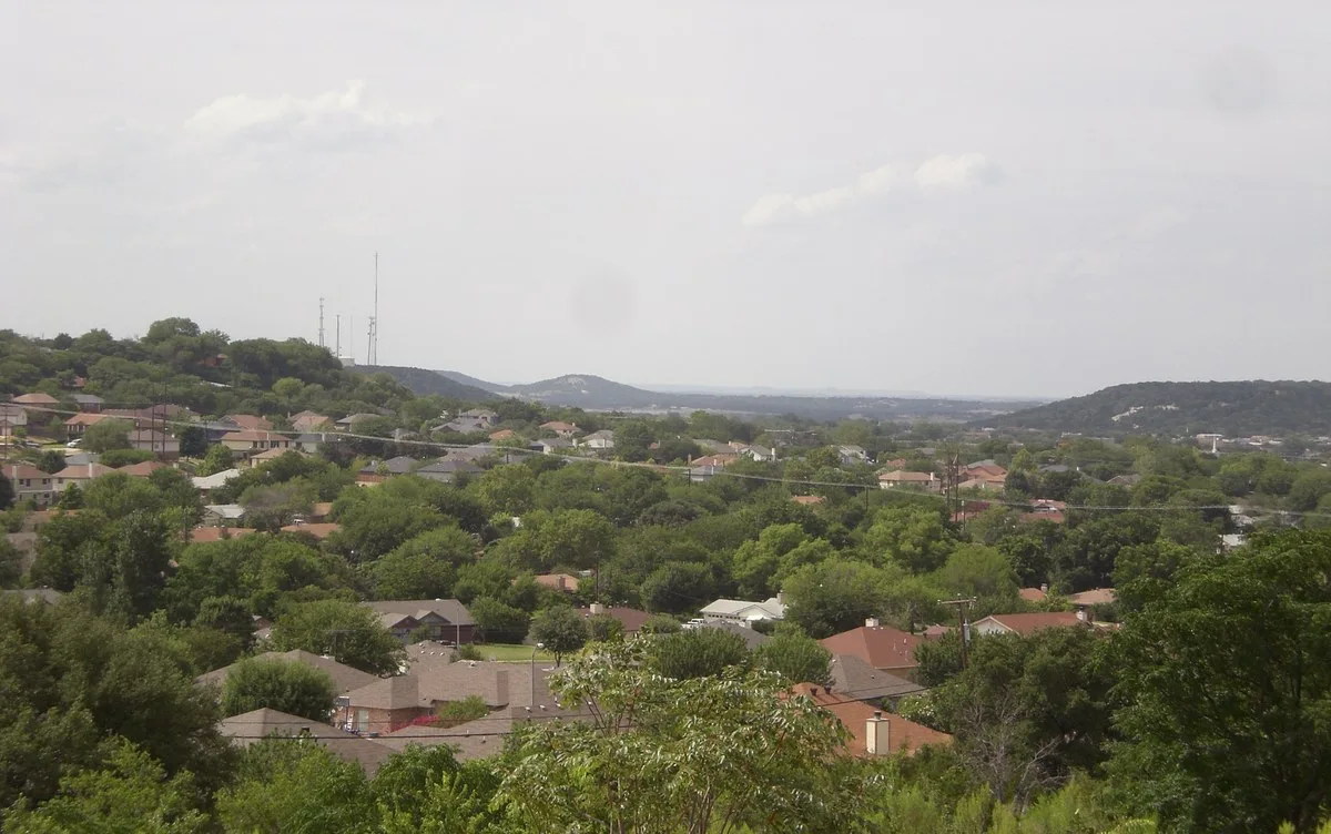 Rooftops and trees of Copperas Cove stretching toward low hills under a cloudy sky