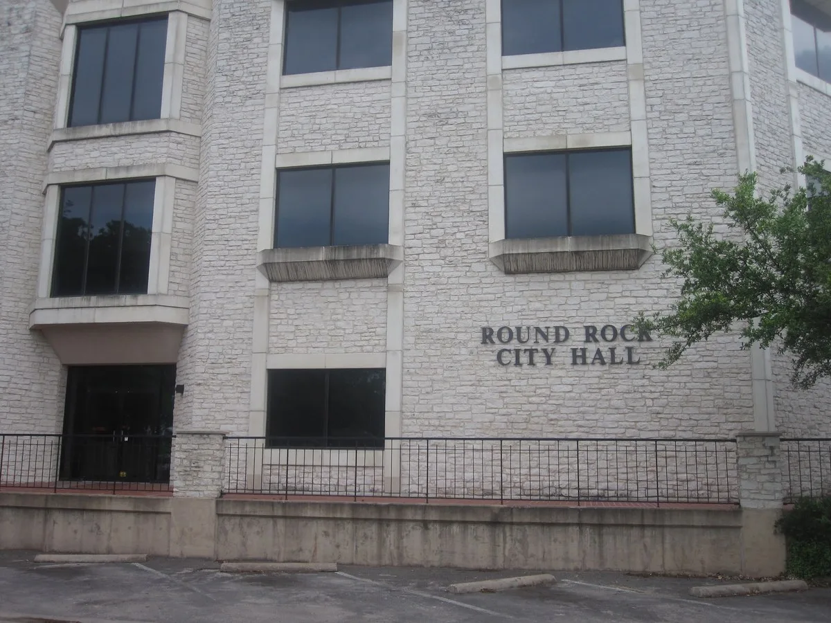 The front of Round Rock City Hall, a light-colored stone building with its name on the wall