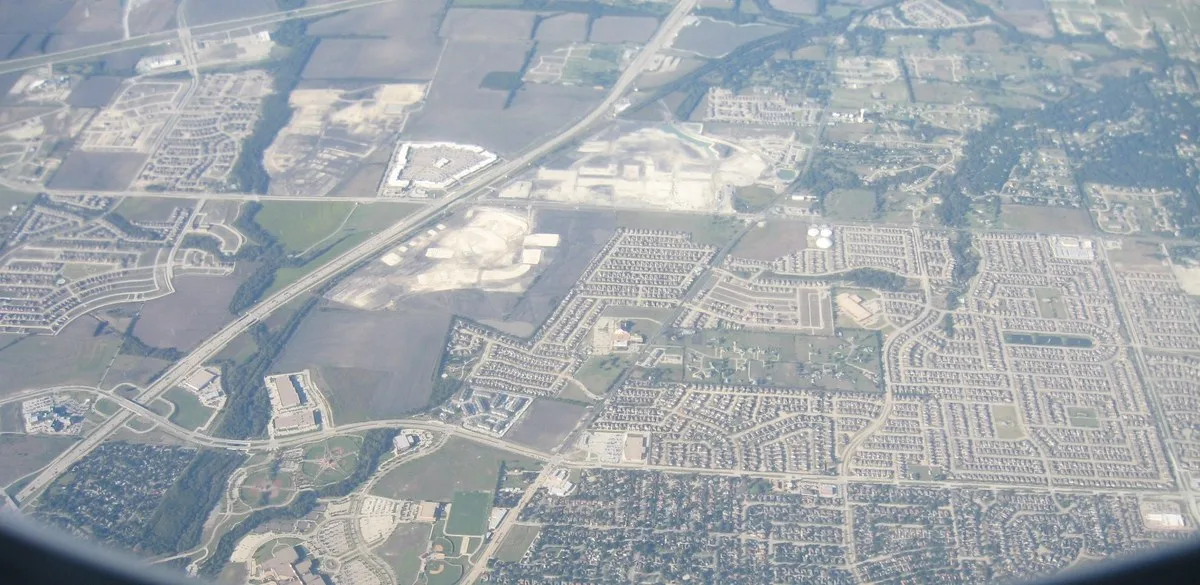 An aerial view through an airplane window of subdivisions, farm fields and U.S. 75 in Collin County