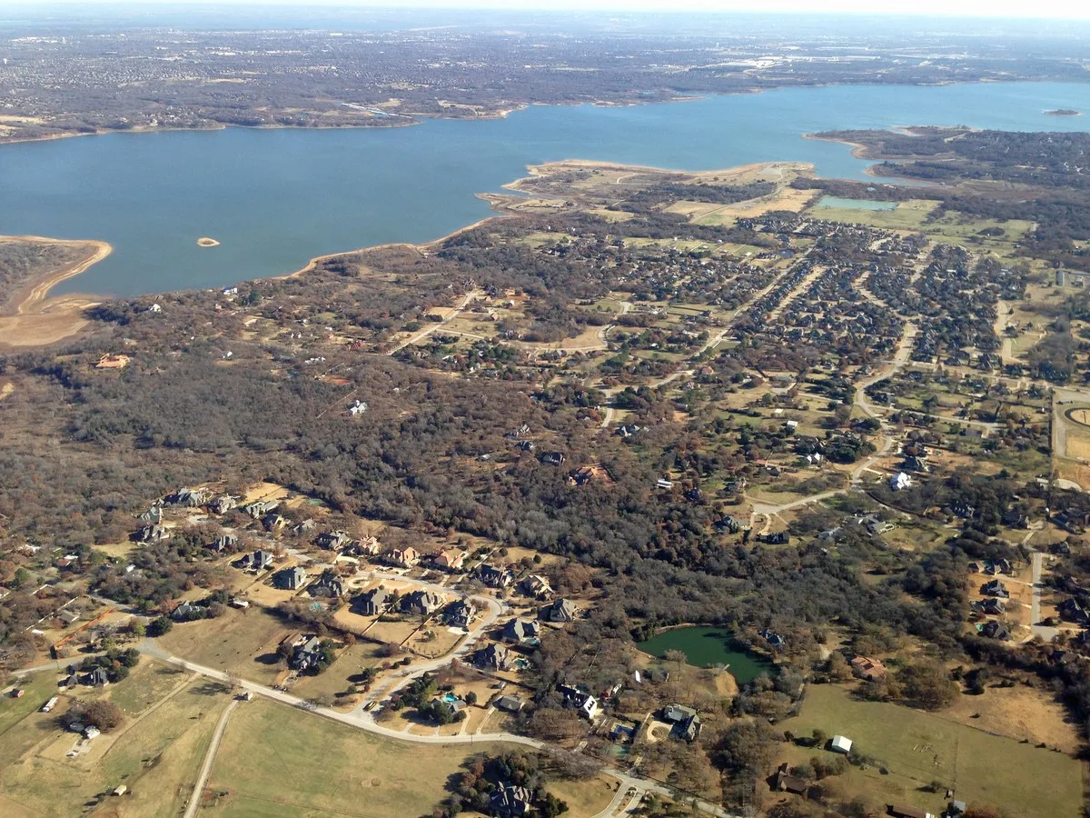 Aerial view of Southlake neighborhoods with tree cover and Lake Grapevine in the distance