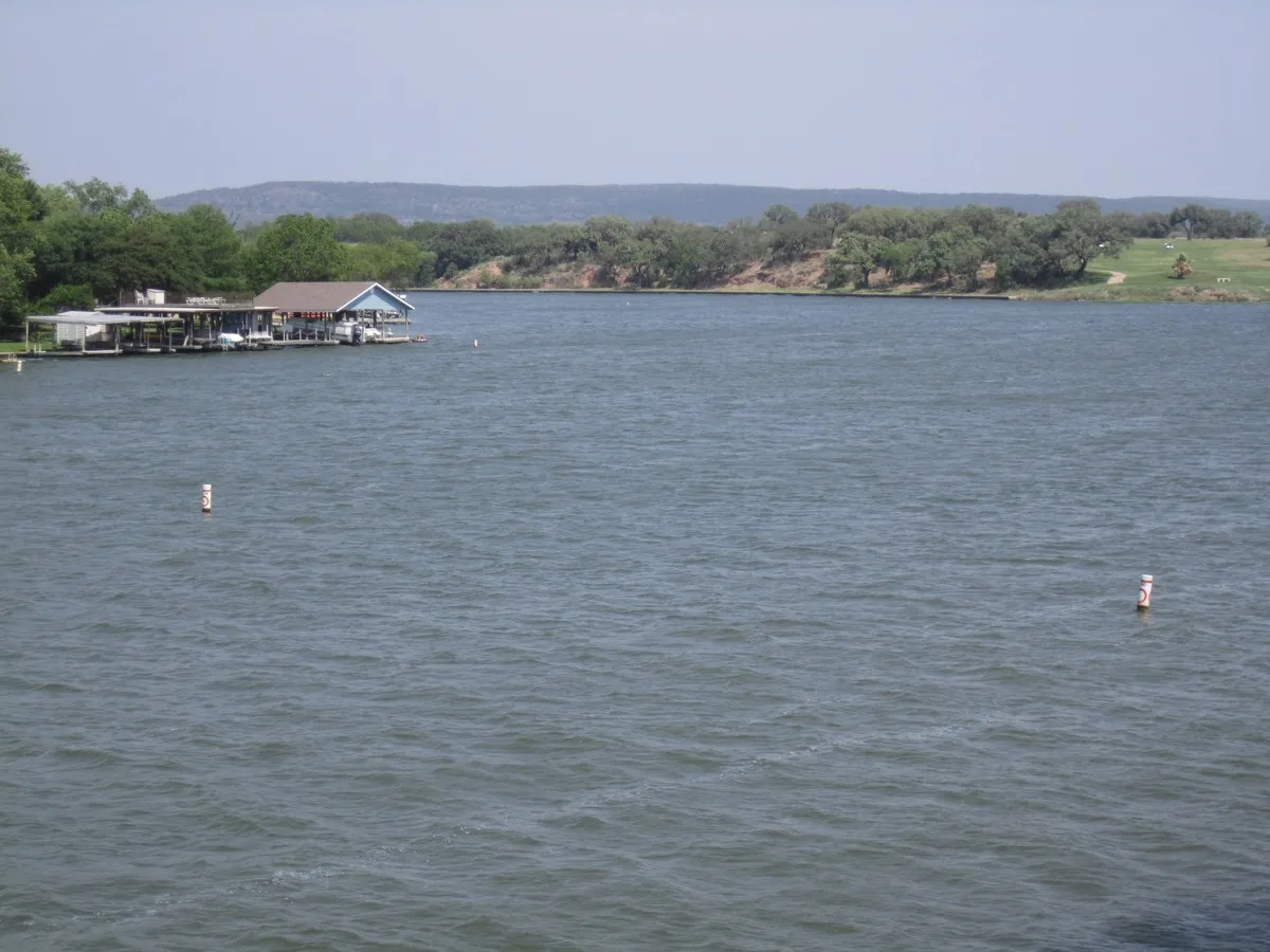 Lake LBJ near Kingsland with a boathouse on the left shore and wooded hills beyond