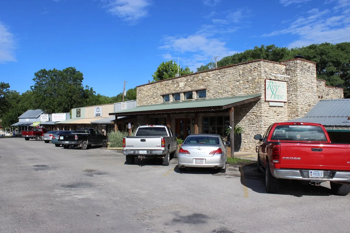 Stone and wood storefronts with pickup trucks parked out front in downtown Wimberley