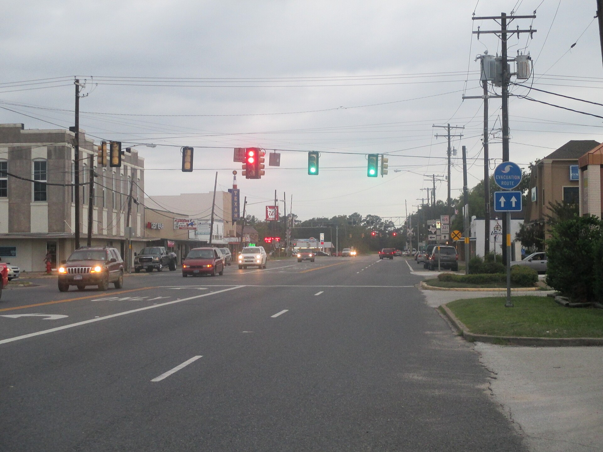 Downtown Cleveland, Texas, looking along a wide commercial highway with storefronts and a railroad crossing sign