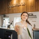female barista at sycamore coffee serving an iced mocha latte