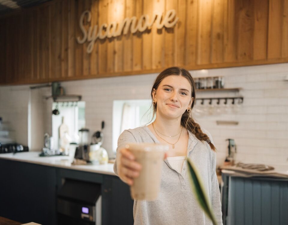 female barista at sycamore coffee serving an iced mocha latte