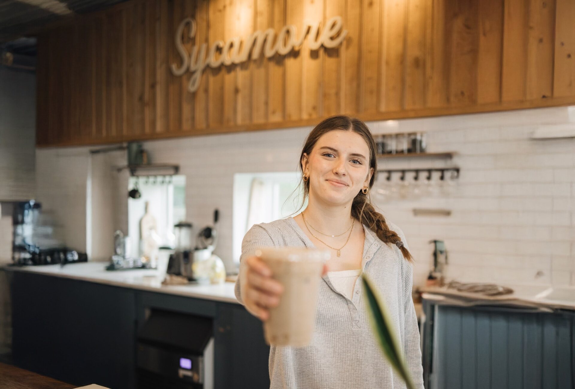female barista at sycamore coffee serving an iced mocha latte