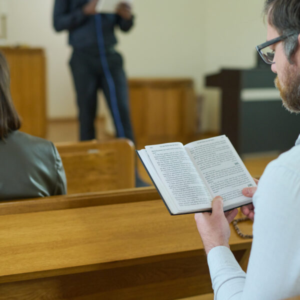 Middle aged man with open Holy Bible reading verses from Gospel in church